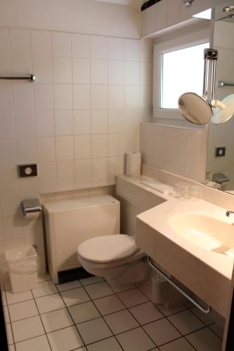 a white bathroom with a toilet and a sink at Landhaus Seeblick in Bitburg
