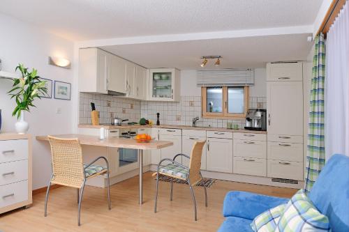 ツェルマットにあるハウス レオポルドの白いキャビネット、テーブルと椅子付きのキッチンが備わります。