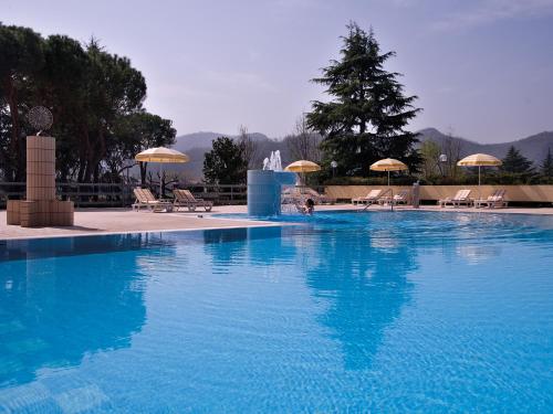 モンテグロット・テルメにあるHotel Terme Marco Poloの青い大型スイミングプール(椅子、パラソル付)