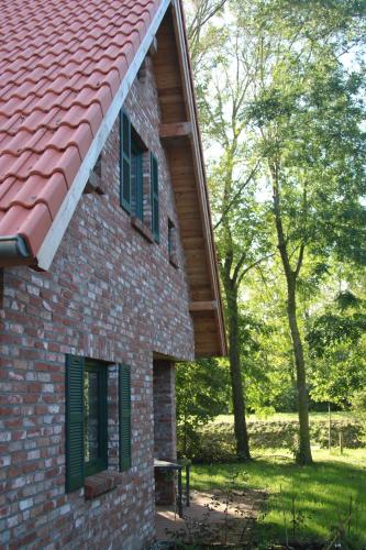 a brick building with green shuttered windows and a bench at Ferienhaus Lee in Pellworm