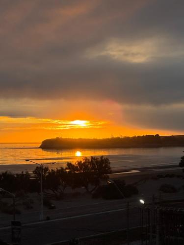 Una puesta de sol sobre un cuerpo de agua con la puesta del sol en Mi Ruca, en Puerto Madryn