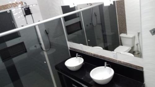 un bagno con 2 lavandini bianchi e uno specchio di Paraíso Escarpas do Lago 1 - Capitólio a Capitólio