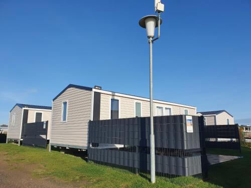 a mobile home behind a fence next to a street light at Campingland Ostsee - Mobilheim A2Meeresbriese in Schashagen
