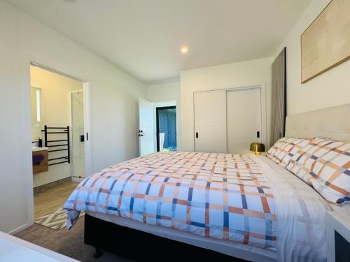 a bedroom with a bed with a colorful comforter at New house has bedroom with attached bathroom in Taupo