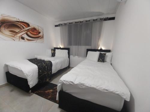 a bedroom with two beds and a table in it at שירת דבורה בבני ברק in Giv‘at Shemuʼel