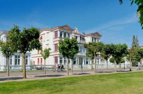 a large white building with trees in front of it at Villa Seeblick Schloonsee in Ahlbeck