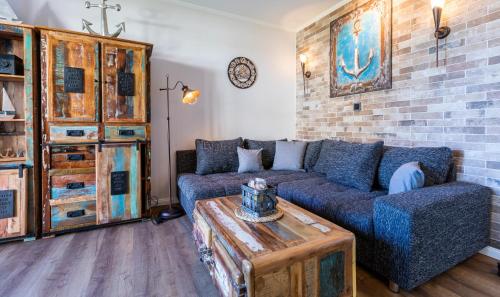 a living room with a blue couch and a brick wall at Terrassen-Fewo "Ankerplatz" direkt am Ostseestrand inkl Schwimmbad in Kronsgaard