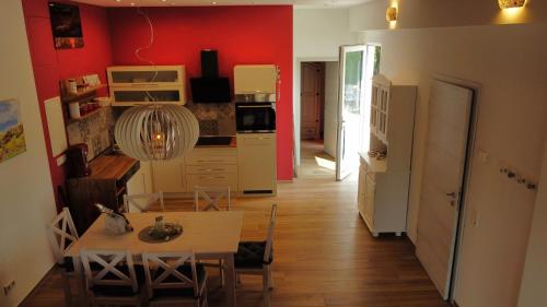 a room with a table and a kitchen with red walls at Birkennest in Bingerbrück