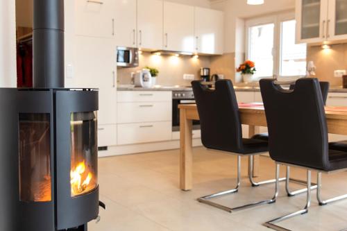 a fireplace in a kitchen with a table and chairs at Wellnesshaus "Welle" eingezäunt in Fehmarn
