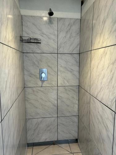 a shower with a tile wall with a urinal at Pousada e Camping do Motochileiro in Urubici