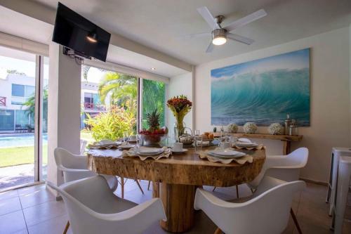 a dining room with a wooden table and white chairs at Villa en Nuevo Vallarta 15 in Nuevo Vallarta