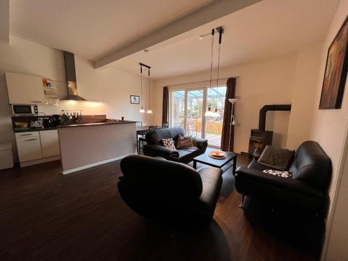 a living room with two couches and a kitchen at Leuchtfeuer Fewo "Catrin" in Börgerende-Rethwisch