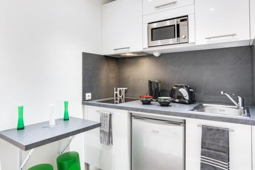 une cuisine avec des armoires blanches et un micro-ondes dans l'établissement Cannes centre Cosy appartement avec mezzanine, à Cannes