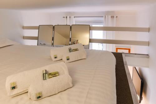 une chambre avec un lit blanc avec des oreillers et un miroir dans l'établissement Cannes centre Cosy appartement avec mezzanine, à Cannes