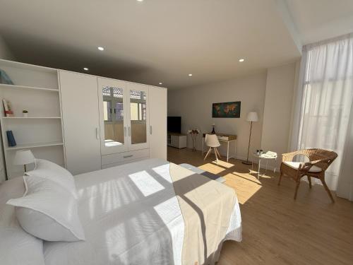 a bedroom with a large white bed and a desk at Suites San Agustín 45 - Adults Only in Icod de los Vinos