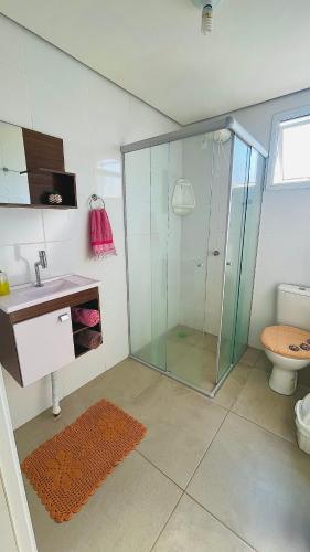 a bathroom with a shower and a sink and a toilet at Ap de 2 quartos com AR, wifi e garagem - Bairro tranquilo in Santo Ângelo