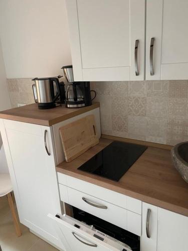 Una cocina con gabinetes blancos y encimera. en Kleines Harztor, en Halberstadt