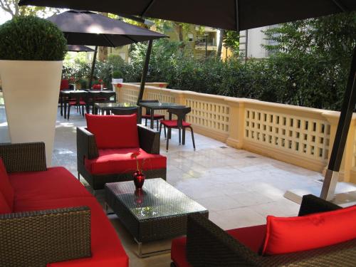 a patio with red chairs and tables and an umbrella at UNAHOTELS Villa dei Platani Foligno in Foligno