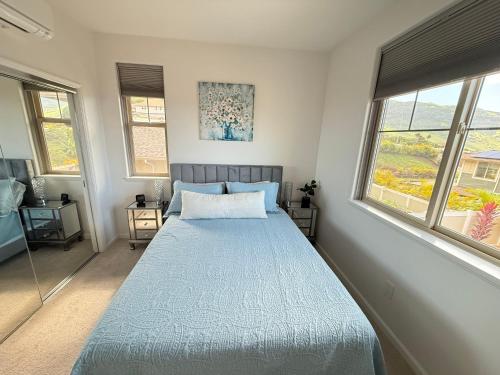 a bedroom with a bed and two windows at New 4 Bedroom Home with Ocean and Gorgeous Mountain Views in the gated community of Mauna Olu in Waianae