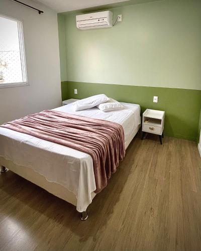 a bed in a room with a green wall at Ap de 2 quartos com AR, wifi e garagem - Bairro tranquilo in Santo Ângelo