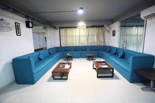 a living room with a blue couch and tables at Super Capital O Levanti Near Aravali Biodiversity Park in Gurgaon