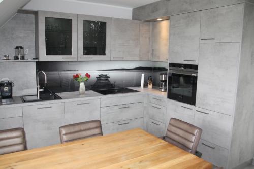 a kitchen with a wooden table and chairs in it at Seeblick 8 - Luxus direkt am Hafen von Norddeich in Norddeich