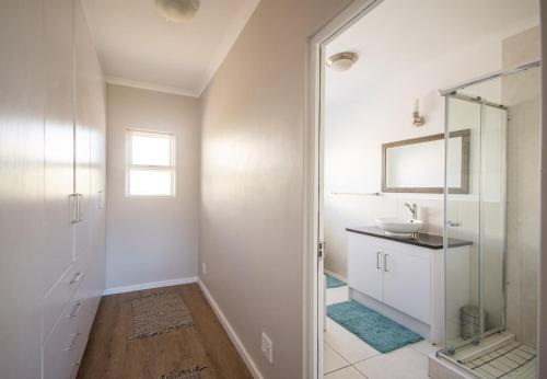 a white bathroom with a sink and a mirror at Capri House in Cape Town
