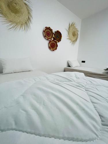 a bedroom with a white bed and two hats on the wall at Maghrib Nomads Hostel in Tamraght Ouzdar