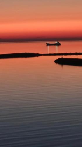 a boat in the middle of the water at sunset at Sunset Apartment in Shëngjin