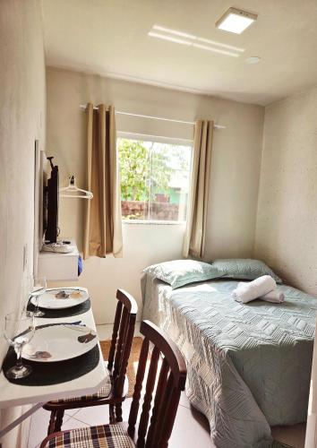ein kleines Schlafzimmer mit einem Bett und einem Tisch und Stühlen in der Unterkunft Studio com ar condicionado e estacionamento gratuito próximo ao aeroporto e praias in Florianópolis