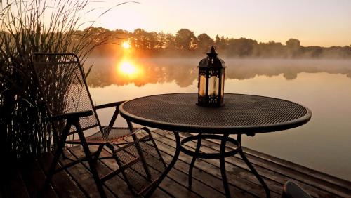 a table with two chairs and a lamp on a dock with a lake at Ferienhaus SEERESIDENZ am Mühlensee in Godern