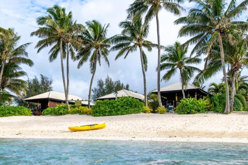 a yellow kayak on a beach with palm trees at Rarotonga Beach Bungalows in Rarotonga