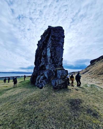 a group of people walking around a rock formation at Hótel Laugarhóll with natural hot spring in Laugarholl