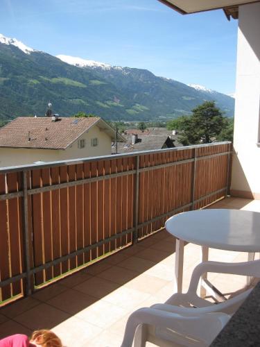 a table and chair on a balcony with mountains at Ferienwohnung im Haus Texel IV in Rablà