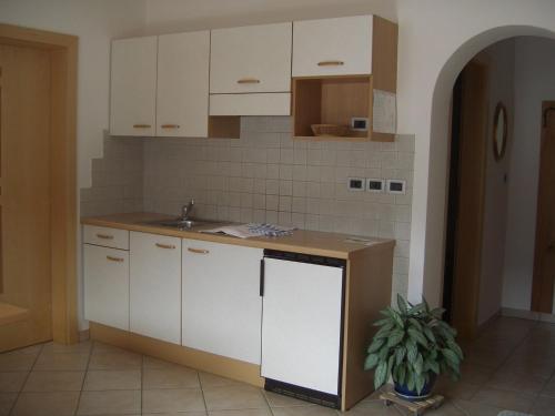 a kitchen with white cabinets and a sink at Ferienwohnung im Haus Texel IV in Rablà