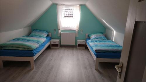 VöhlにあるFerienhaus Scheererのベッド2台と窓が備わる屋根裏部屋です。
