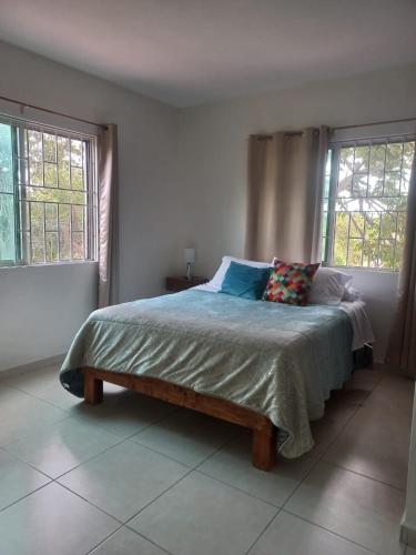 a bed in a bedroom with two windows at Family apartment in excellent location in Tampico