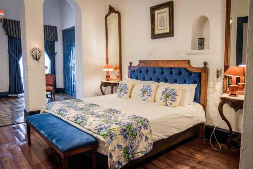 a bedroom with a large bed with a blue headboard at Hostería Hacienda Pinsaqui in Otavalo