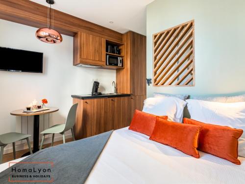 - une chambre avec un lit doté d'oreillers orange et d'une table dans l'établissement Studios Part-Dieu Gare - HomaLyon, à Lyon