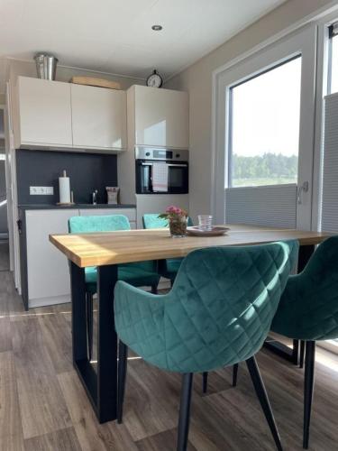 a kitchen with a wooden table and green chairs at Hausboot Heaven on Earth in Klitten