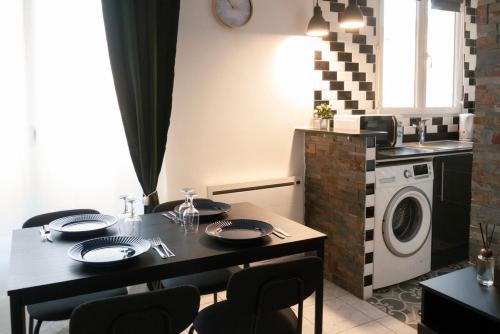 une cuisine avec une table et une machine à laver dans l'établissement L'Émeraude Porte de Paris - Aéroport CDG, Stade de France, Metro 12, à Aubervilliers