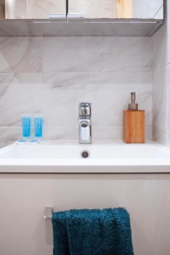 La salle de bains est pourvue d'un lavabo et d'une serviette bleue. dans l'établissement L'Émeraude Porte de Paris - Aéroport CDG, Stade de France, Metro 12, à Aubervilliers