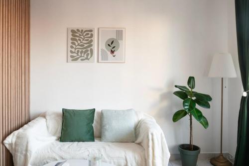 un salon avec un canapé blanc et une plante dans l'établissement L'Émeraude Porte de Paris - Aéroport CDG, Stade de France, Metro 12, à Aubervilliers