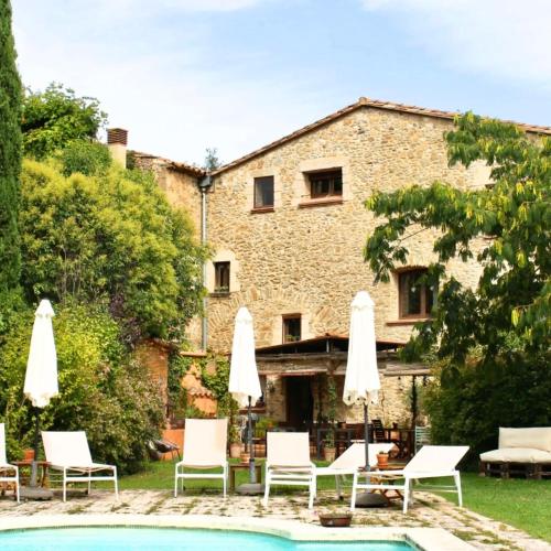a pool with chairs and umbrellas in front of a building at La Lolita ( Adults Only ) in Sant Martí Vell