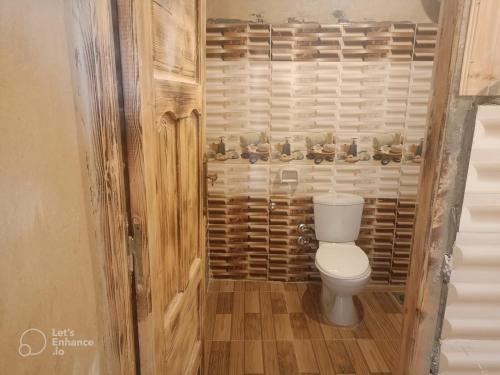 a bathroom with a toilet and a wooden wall at Karam Siwa Camp in Siwa