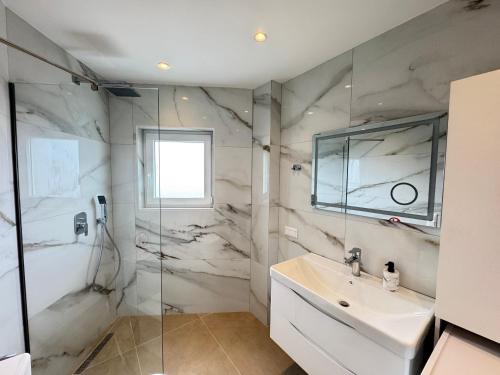 a bathroom with a sink and a glass shower at Casa Bianca Corfu Town in Agios Rokkos