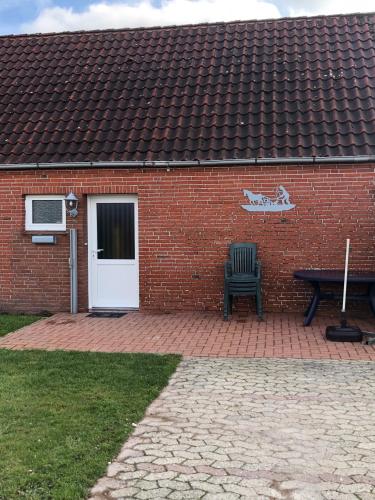 a brick building with a bench and a white door at Ferienhaus Ostfriesland in Berumbur