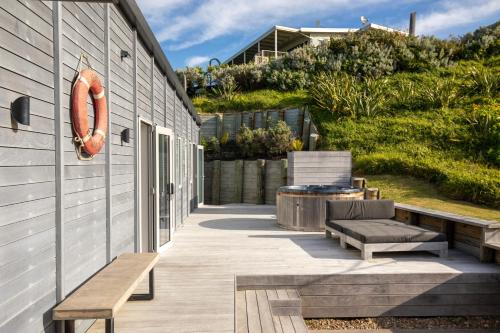a patio with two chairs and a bench at Ocean Beach Retreat in Raglan