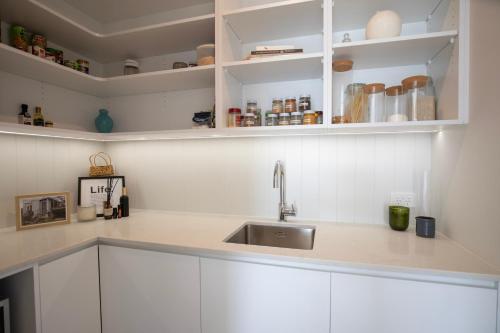 a kitchen with white cabinets and a sink at Ocean Beach Retreat in Raglan