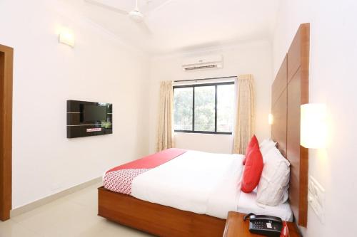 a bedroom with a bed and a tv on the wall at Super Townhouse Dona Castle in Kollam
